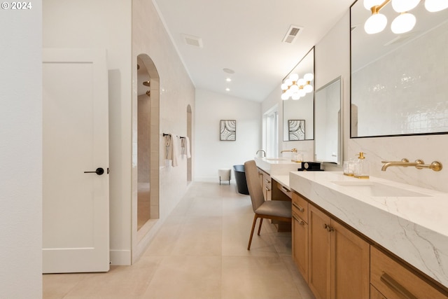 bathroom featuring vanity, vaulted ceiling, tile patterned flooring, and a tile shower