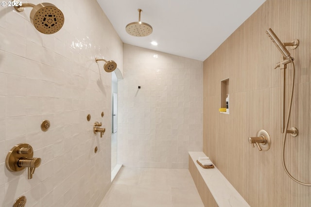 bathroom with tile patterned floors, a tile shower, and vaulted ceiling