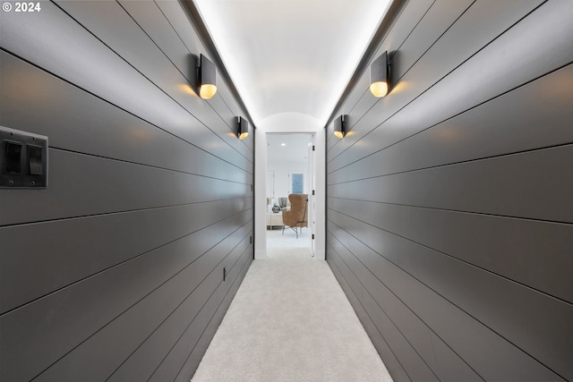 hall with wood walls and light colored carpet