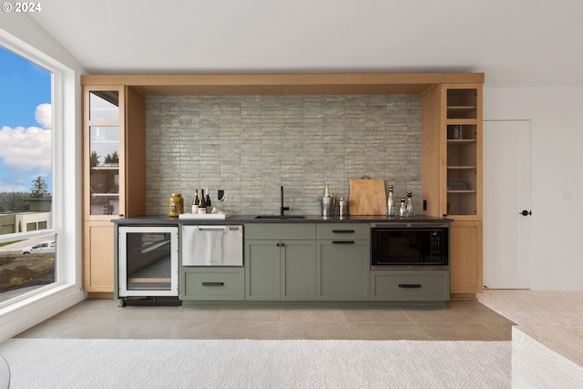 bar with green cabinetry, black microwave, light tile patterned floors, sink, and wine cooler