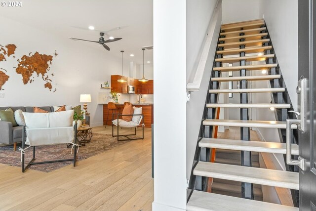 stairs with hardwood / wood-style flooring and a ceiling fan