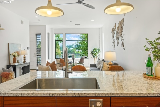 kitchen with brown cabinets, light stone countertops, open floor plan, and a sink