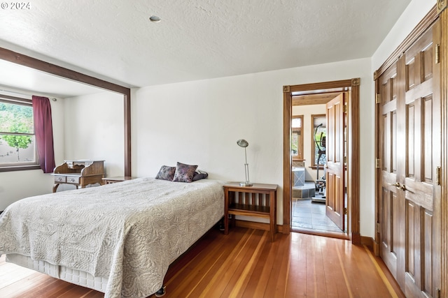 bedroom with a closet, a textured ceiling, and hardwood / wood-style flooring