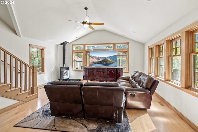 living room featuring a wood stove, lofted ceiling, ceiling fan, and a healthy amount of sunlight