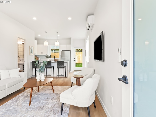 living room featuring baseboards, light wood finished floors, a wall mounted air conditioner, and recessed lighting