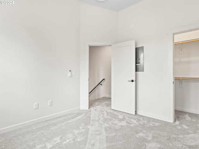 unfurnished bedroom featuring a spacious closet, a closet, a high ceiling, and light carpet