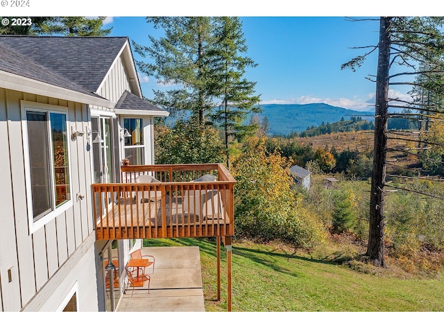 wooden terrace featuring a mountain view, a yard, and a patio