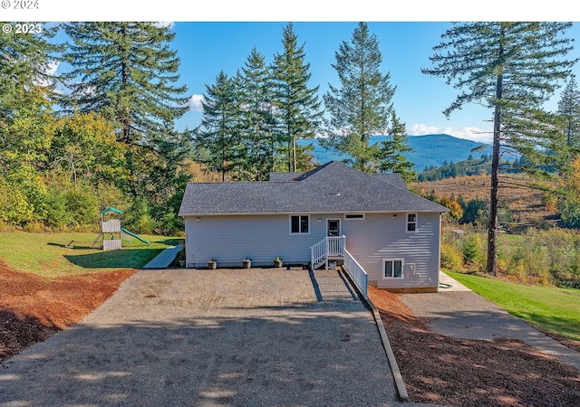 view of front facade featuring a mountain view, a playground, and a front yard