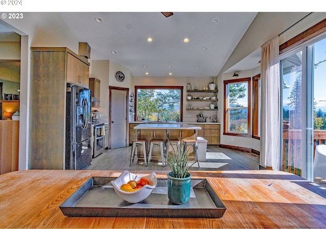 dining room with light wood-type flooring, lofted ceiling, and sink