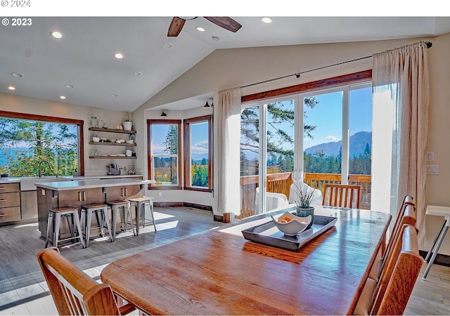 dining space featuring ceiling fan, wet bar, a mountain view, lofted ceiling, and light wood-type flooring