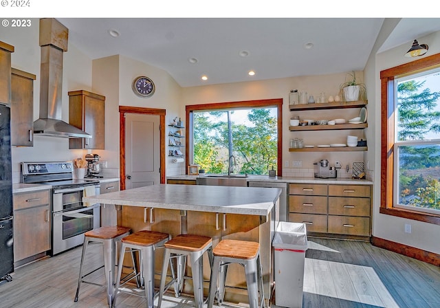 kitchen featuring a center island, wall chimney range hood, sink, and appliances with stainless steel finishes