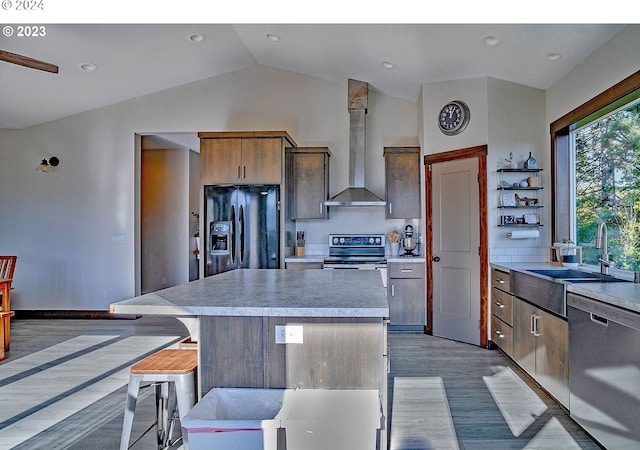 kitchen with a kitchen breakfast bar, a center island, appliances with stainless steel finishes, and vaulted ceiling