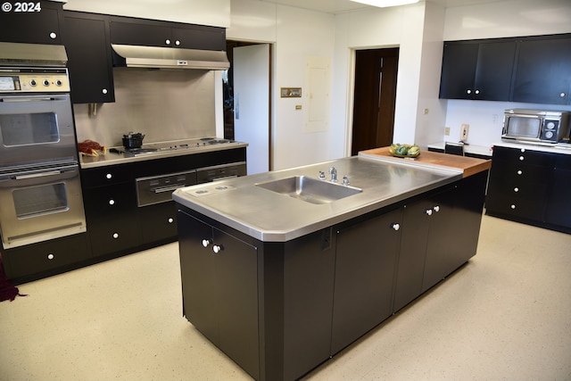 kitchen featuring stainless steel counters, sink, white gas stovetop, range hood, and an island with sink