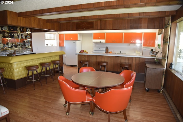 dining room featuring light wood-type flooring, wooden walls, and sink