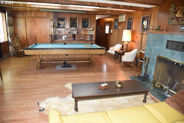 playroom with pool table, a high end fireplace, a wall mounted AC, wooden walls, and hardwood / wood-style flooring