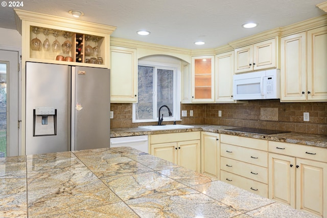 kitchen featuring decorative backsplash, sink, white appliances, and cream cabinetry