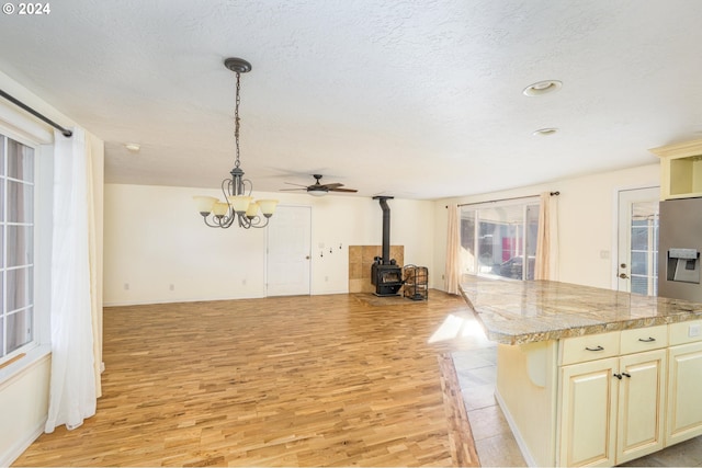 kitchen featuring a wood stove, a wealth of natural light, decorative light fixtures, and light wood-type flooring