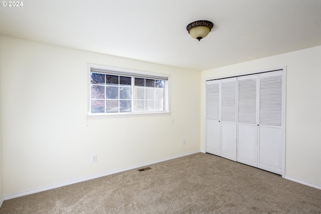 unfurnished bedroom featuring light colored carpet and a closet