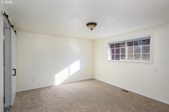 carpeted spare room featuring a barn door