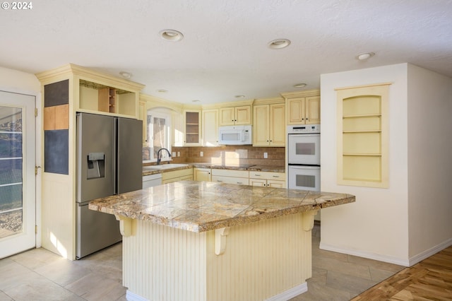 kitchen with a kitchen bar, backsplash, a kitchen island, and white appliances