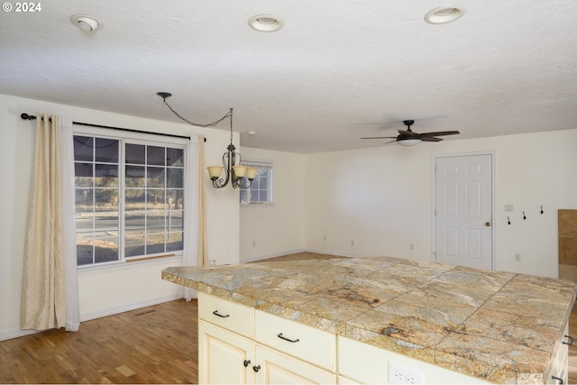 kitchen with a textured ceiling, plenty of natural light, ceiling fan with notable chandelier, and light hardwood / wood-style flooring