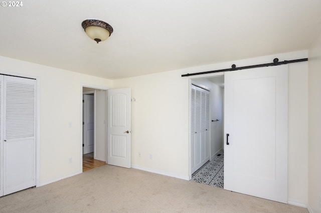 unfurnished bedroom with a barn door and light colored carpet