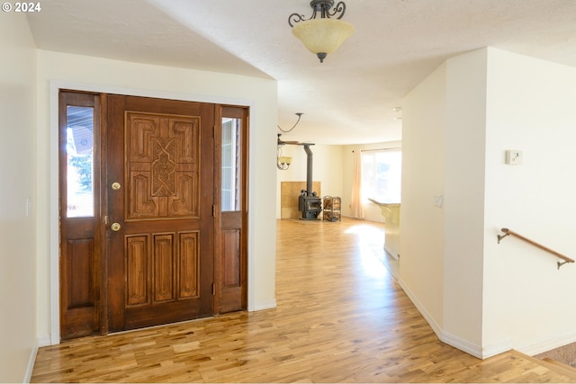 foyer with light hardwood / wood-style floors and a wood stove