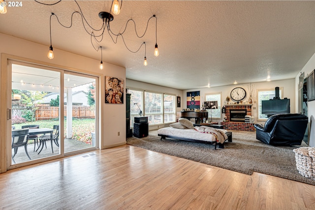 living room with hardwood / wood-style floors, a textured ceiling, and a brick fireplace