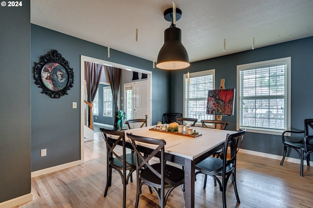 dining area with a textured ceiling and light wood-type flooring