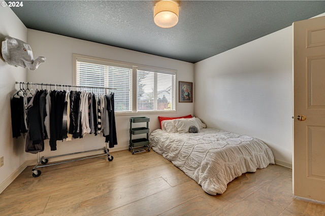 bedroom featuring a textured ceiling and light hardwood / wood-style flooring