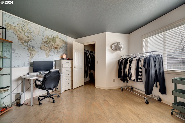 home office with a textured ceiling and light wood-type flooring