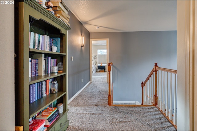 corridor featuring a textured ceiling and light carpet