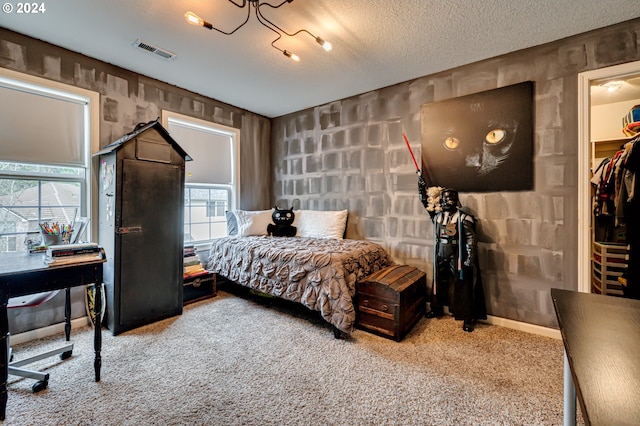 bedroom featuring multiple windows, a spacious closet, carpet floors, and a textured ceiling