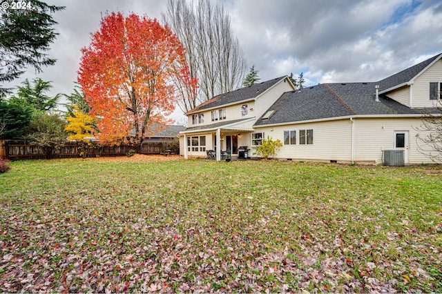 rear view of property featuring a lawn and cooling unit