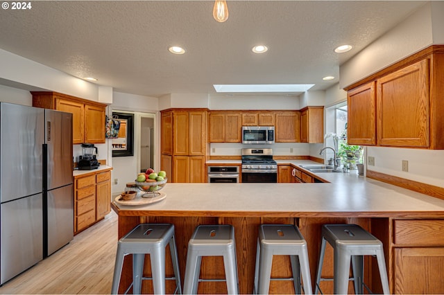 kitchen featuring a kitchen breakfast bar, sink, stainless steel appliances, and a skylight