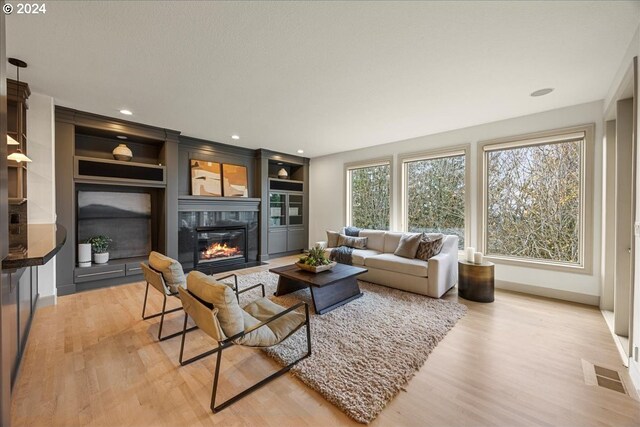 living room featuring built in features and light hardwood / wood-style flooring