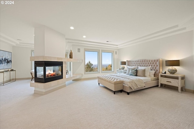 carpeted bedroom with a multi sided fireplace and a tray ceiling