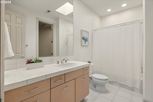 full bathroom with vanity, a skylight, tile patterned flooring, toilet, and shower / bath combo with shower curtain