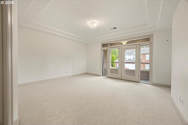 carpeted empty room featuring a raised ceiling and french doors