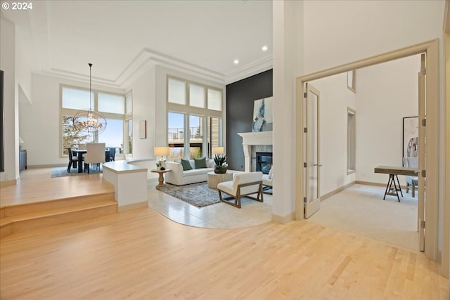 living room featuring a towering ceiling, light wood-type flooring, and an inviting chandelier