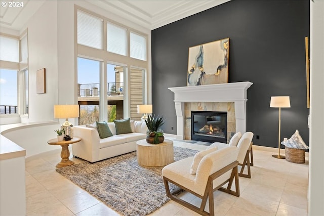 sitting room featuring a tile fireplace, light tile patterned floors, a towering ceiling, and ornamental molding