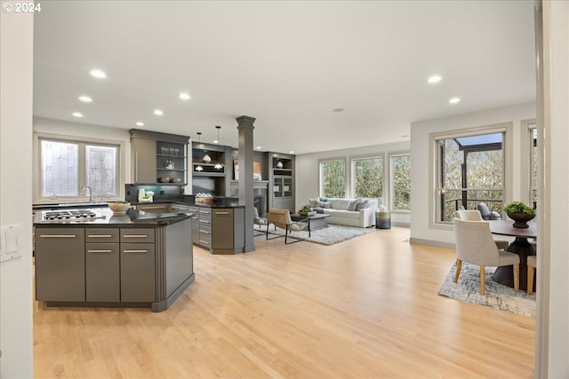 kitchen featuring gray cabinets, light hardwood / wood-style floors, a kitchen island, and stainless steel gas stovetop