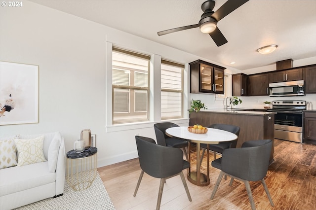 kitchen with sink, light hardwood / wood-style flooring, ceiling fan, stainless steel range, and dark brown cabinets