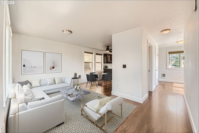 living room featuring hardwood / wood-style floors, ceiling fan, and a textured ceiling