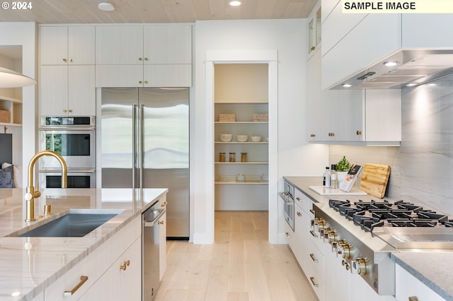 kitchen featuring white cabinetry, sink, stainless steel appliances, ventilation hood, and light wood-type flooring