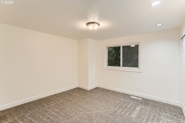 unfurnished room with carpet and a textured ceiling