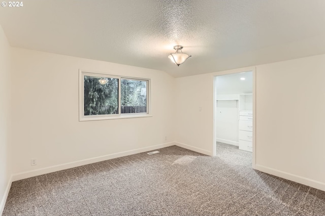 unfurnished room with carpet and a textured ceiling