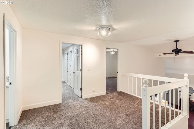 unfurnished room with ceiling fan, a textured ceiling, and dark colored carpet