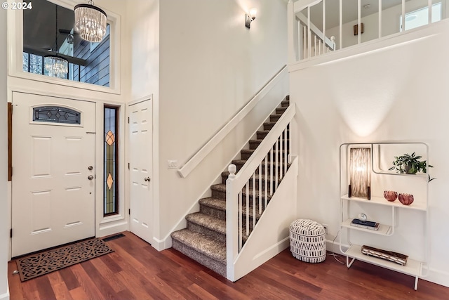 foyer featuring a towering ceiling, dark hardwood / wood-style floors, and a notable chandelier