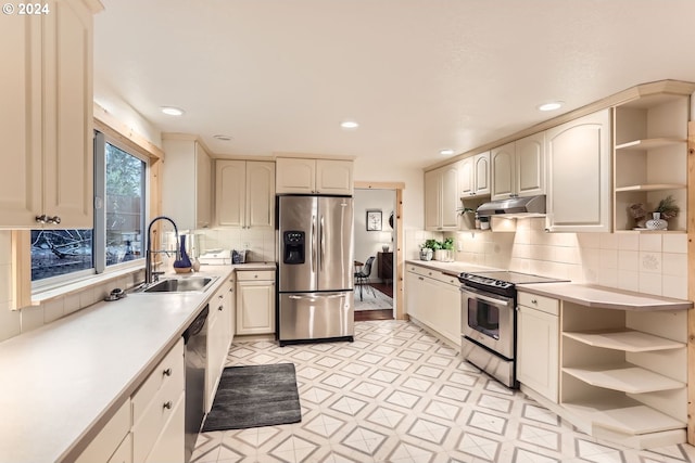 kitchen with backsplash, sink, stainless steel appliances, and cream cabinets